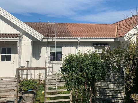 Hvitt hus med teglsteinstak og stige mot taket