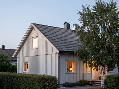 Lyst trehus med rent, mørkt tak i kveldslys